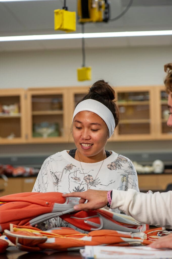 Biology lab student with anatomy model hand