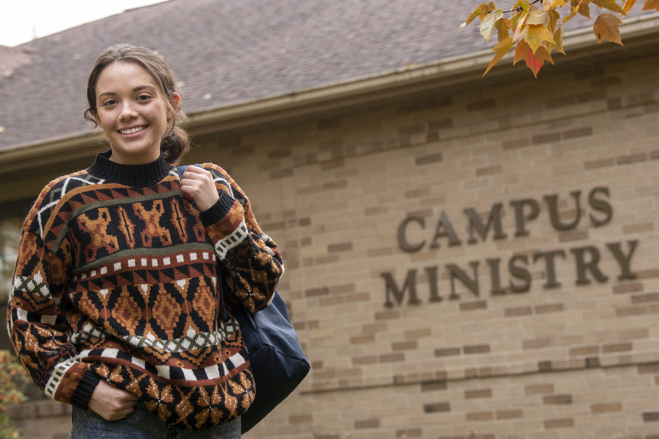 Smiling student in front of campus ministry building