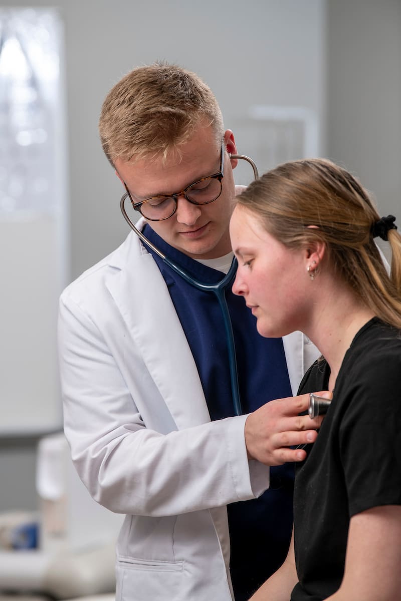 Physician Assistant listens to heartbeat of patient.