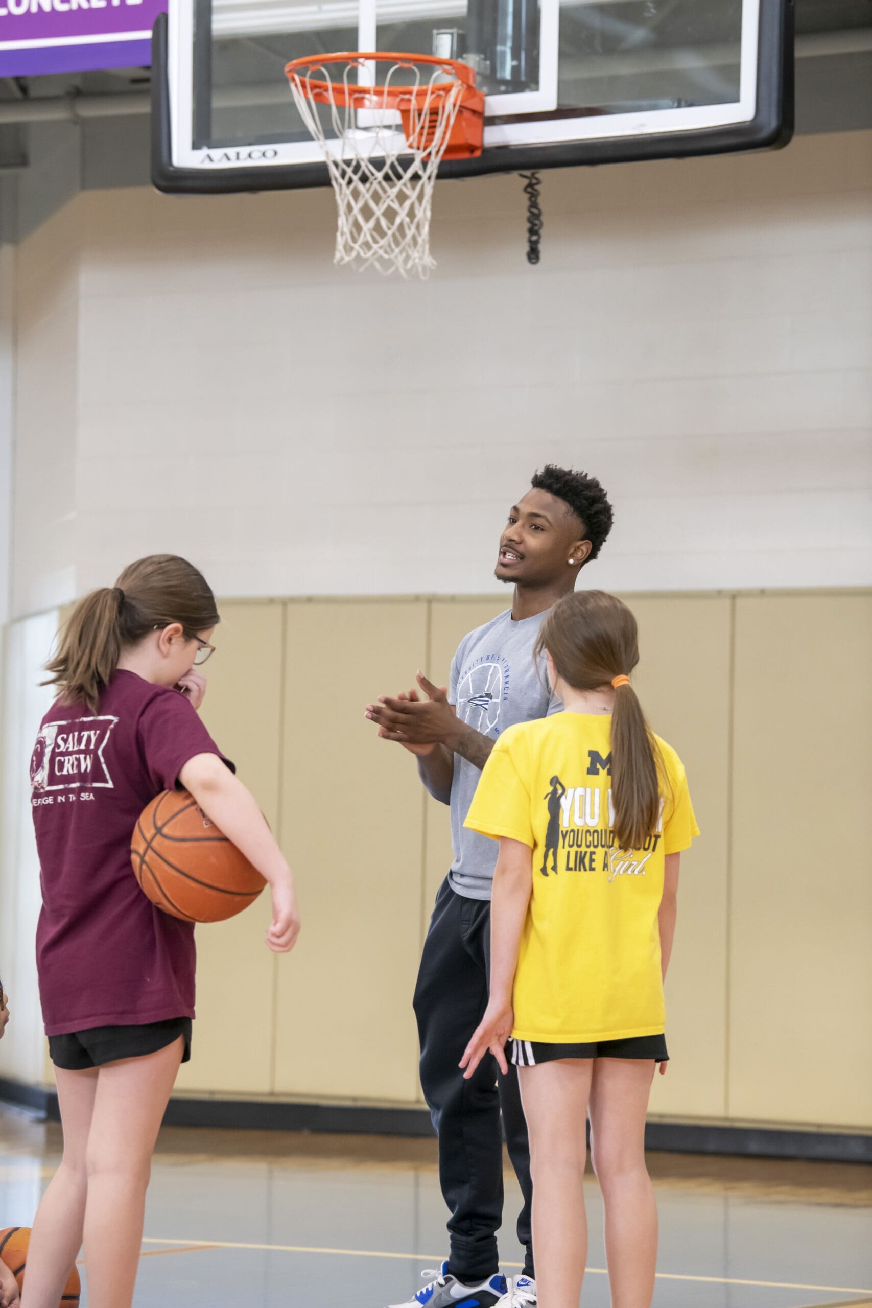 Student instructors coach young students on basketball.