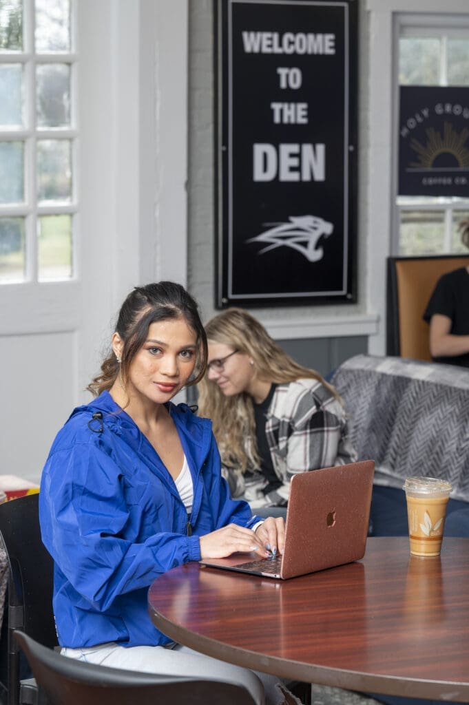 Student works on laptop in coffee house on campus