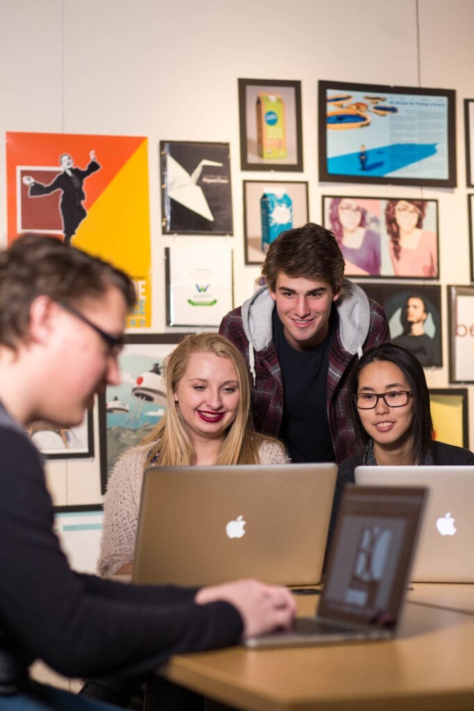 Three Graphic Design Students looking at laptop
