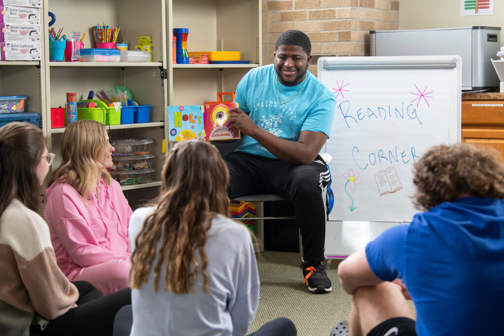 SF students reading a picture book to other students. 