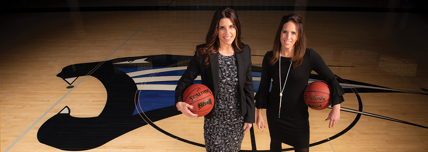 Sisters Trisha Paul (BS ’93) and Emily Szaferski (BA '00) hold basketballs in Hutzell Gymnasium