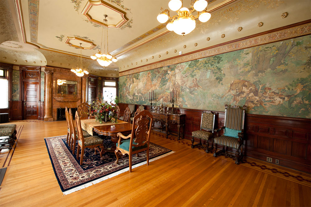 The 30-foot dining room was styled in the Italian Renaissance, with vaulted ceilings and high style ornamentation. Above the dark wood wainscoating is a mural entitled “The Hunt,” which is painted on canvas by the artist Holslag – who also supervised all mural paintings in the Library of Congress, including painting murals in the Office of the of Congress.