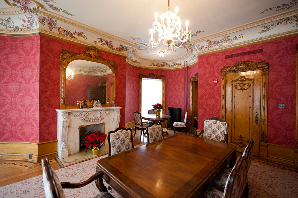 This elegant guest bedroom now has deep rose-colored wall coverings, replicating the original. Along with the delicately scrolled, flowered carpeting, the décor explains why the room has been popularly referred to as the Pink Room or Rose Room. Wall coverings, carpets and lights were selected to closely match the originals.