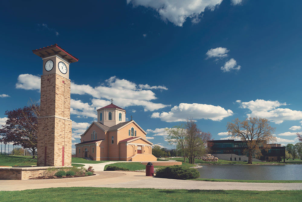 The St. Francis Chapel and clocktower on a sunny day with white puffy clouds in the sky