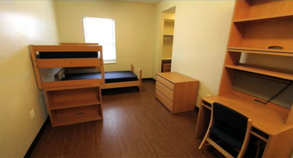 Undecorated room in Clare Hall with 2 beds, dressers, desks, and chairs